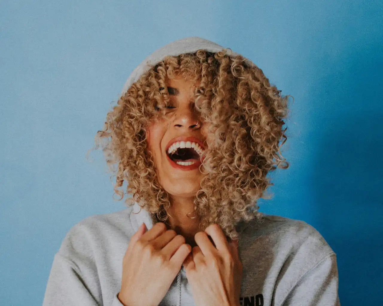 Happy woman with curly hair and hoody wearing cheap contact lenses from the optical. co