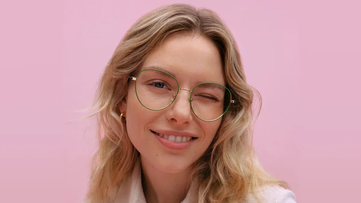 Woman wearing green metal eyeglasses winking at camera