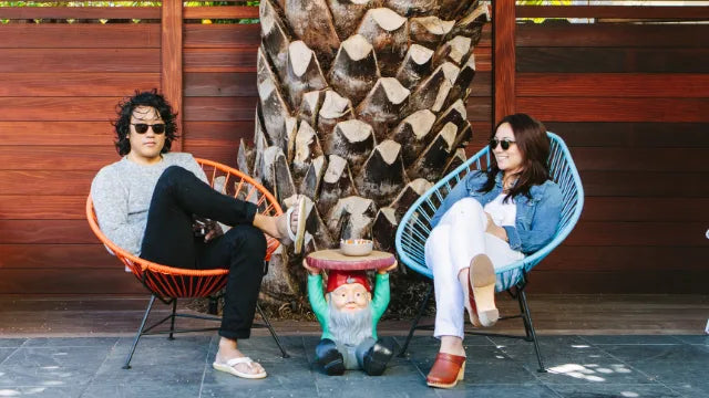 Couple sitting in front of giant palm wearing GLCO bio acetate earth friendly glasses