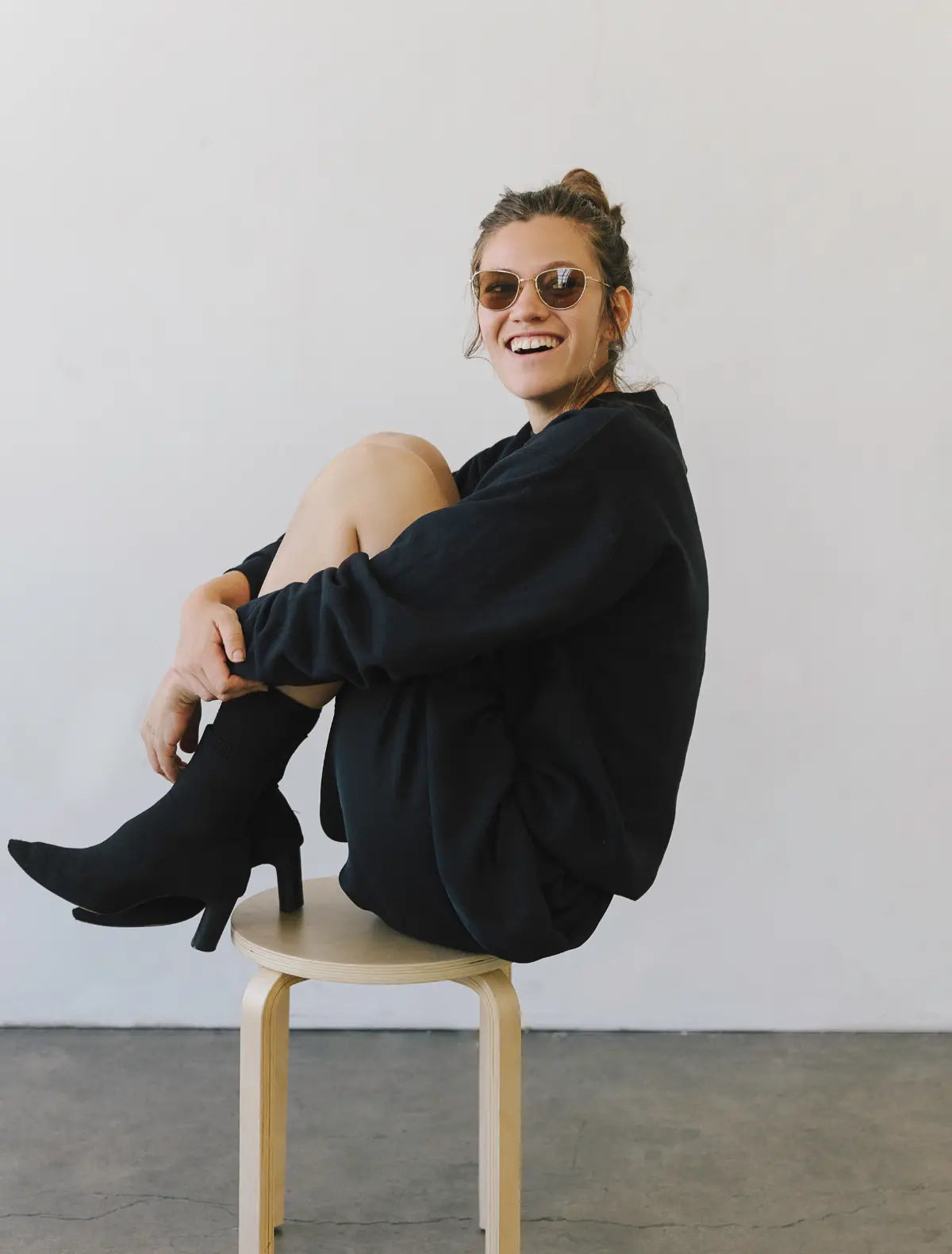 Happy woman sitting on stool wearing polarized metal sunglasses from The Optical Co