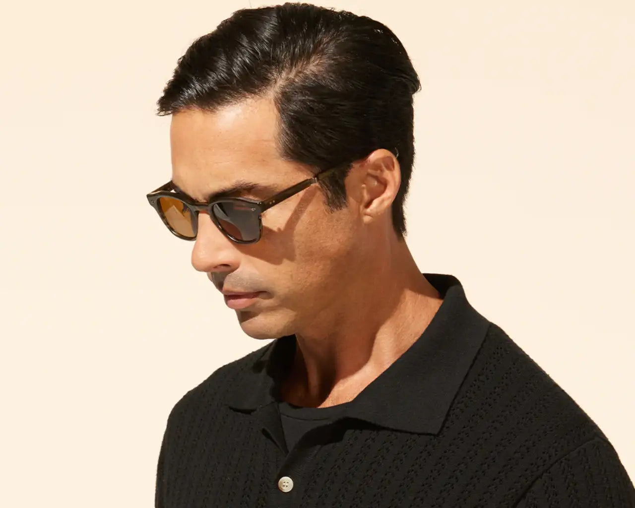 Man wearing luxury sunglasses and black shirt on tan background. Image by Mr. Leight