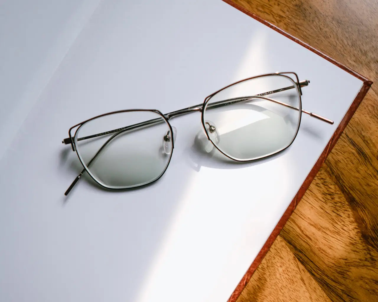 Trendy metal eyeglasses sitting on open journal