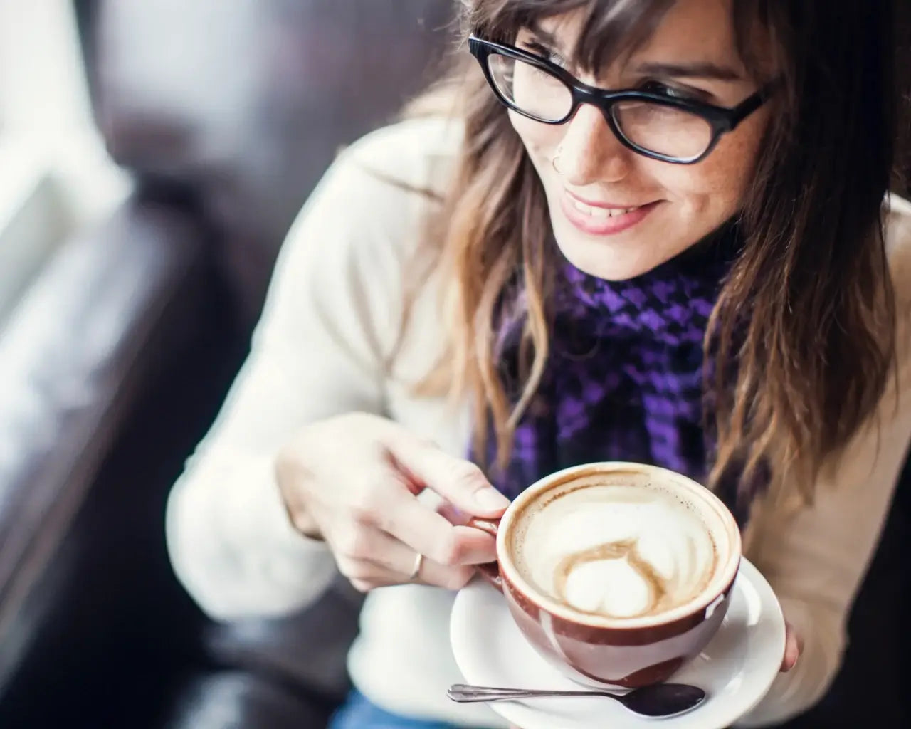 Woman wearing glasses drinking a latte