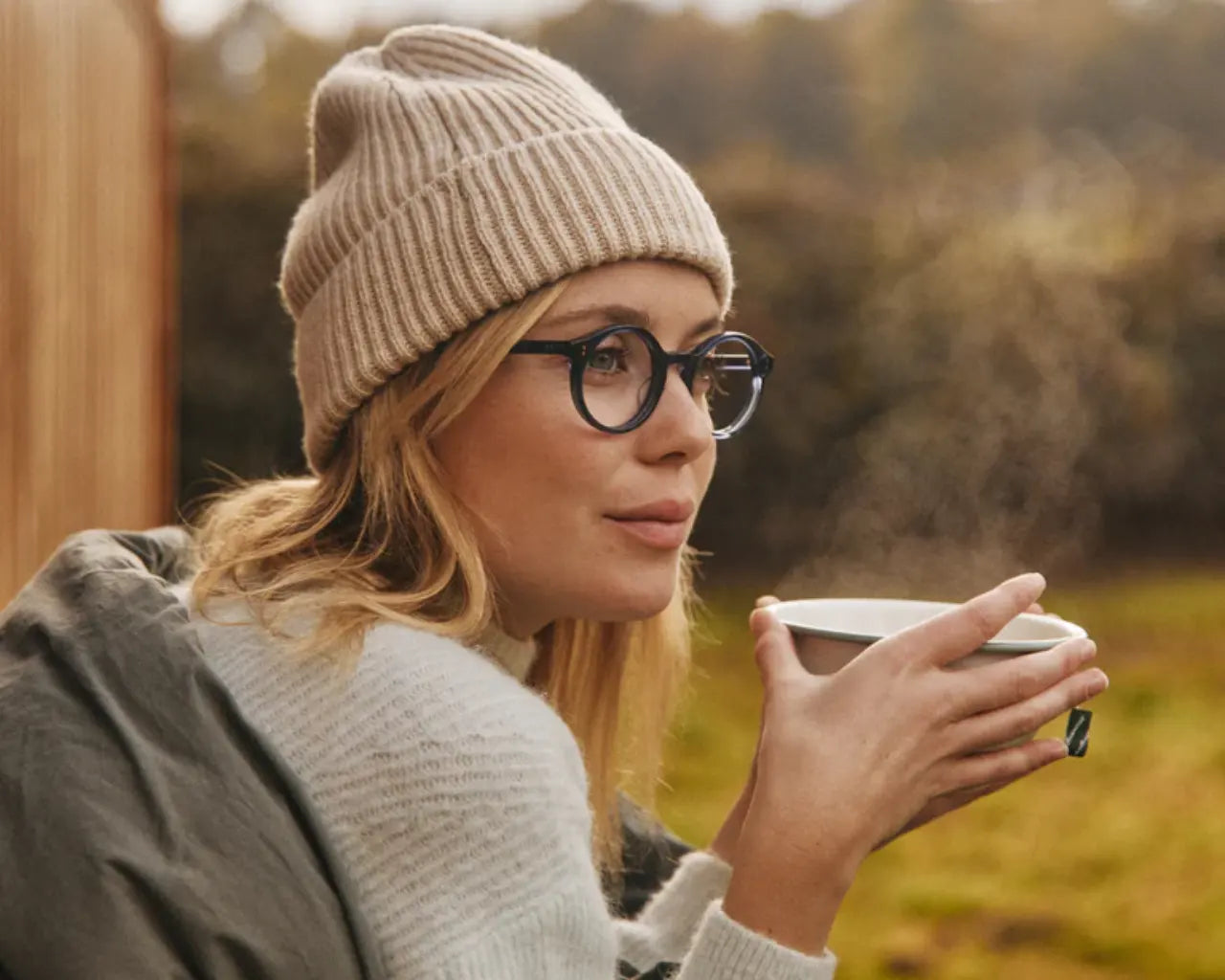 Woman sipping a warm drink wearing SALT. round plastic luxury eyeglasses from The Optical Co