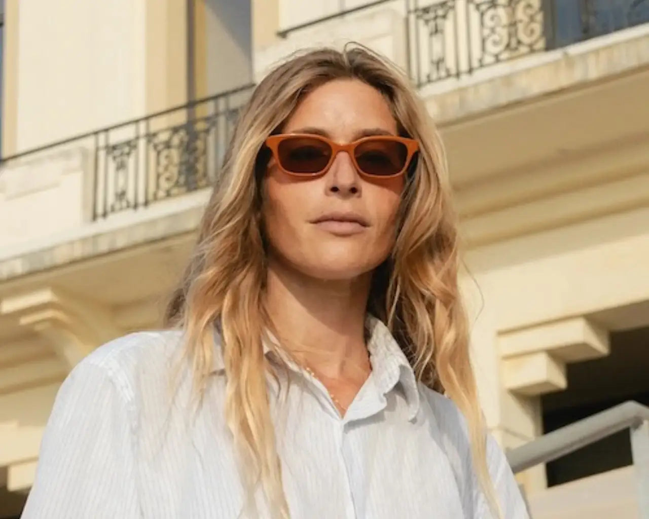 Woman wearing orange GLCO sunglasses and a white shirt. Photo credit: GLCO