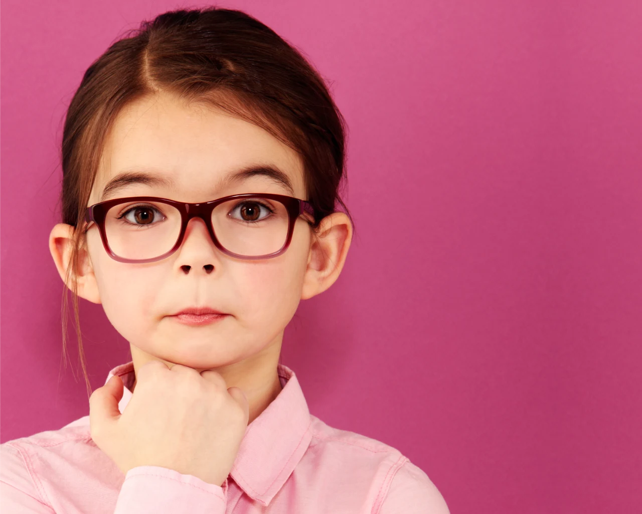 Young child wearing glasses and pink collar shirt with surprised look