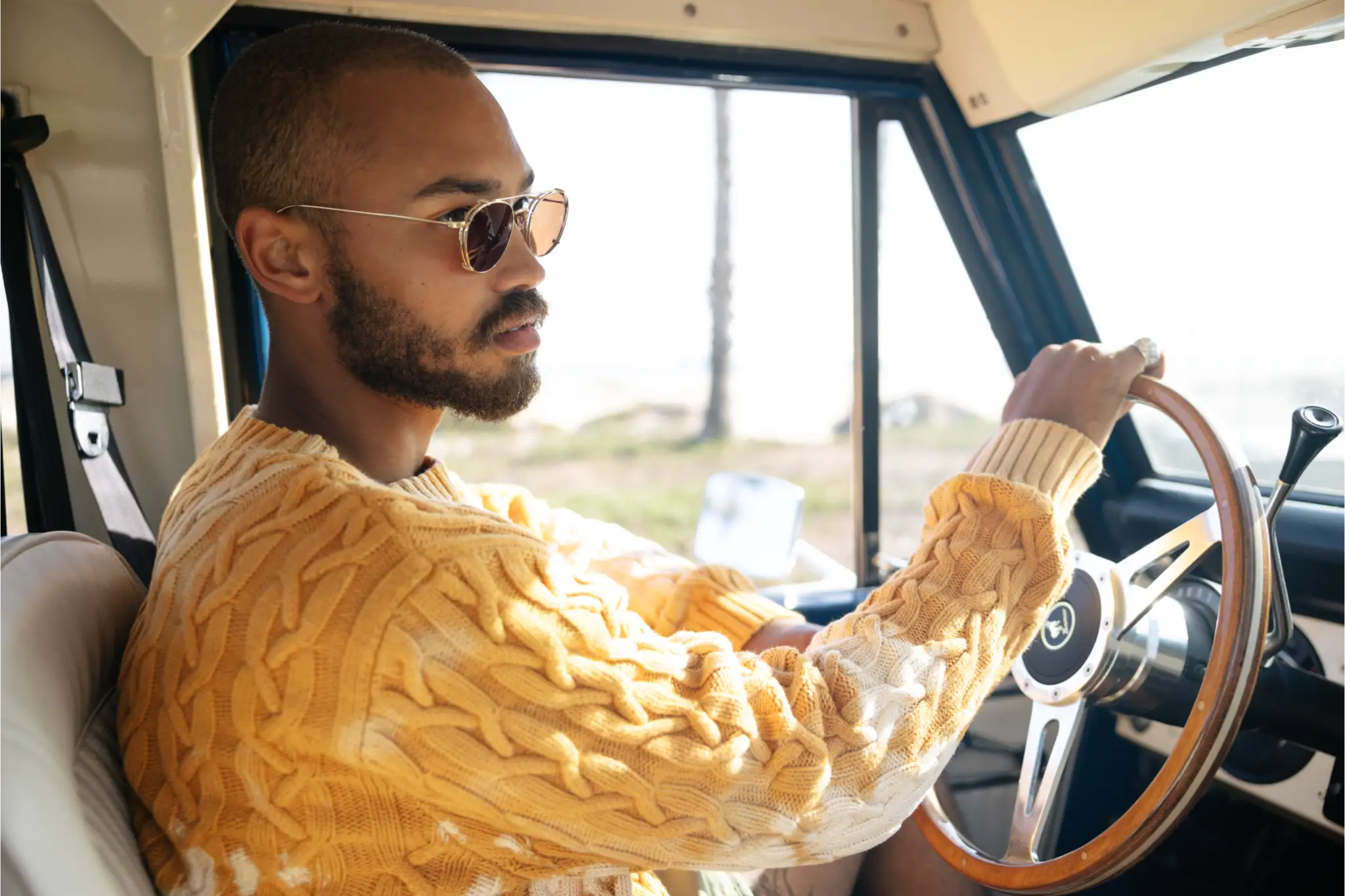 Man in a yellow sweater sitting inside a vintage bronco wearing Garrett Leight glasses with clip on sunglasses. Image courtesy of GLCO