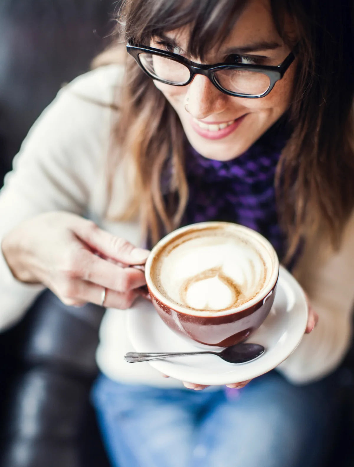 Woman wearing luxury eyeglasses and drinking a latte in a coffee shop